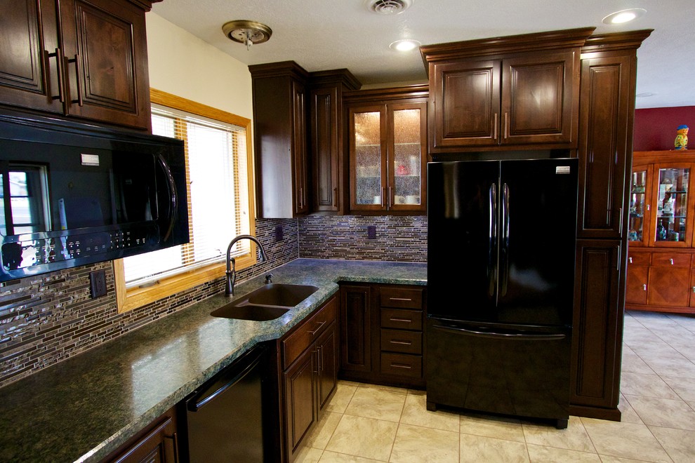 Kitchen - mid-sized u-shaped kitchen idea with an undermount sink, dark wood cabinets, laminate countertops, multicolored backsplash, glass tile backsplash, black appliances and an island