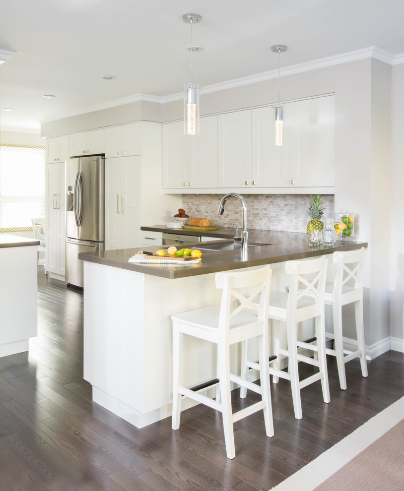 Eat-in kitchen - large transitional l-shaped dark wood floor and brown floor eat-in kitchen idea in Toronto with an undermount sink, shaker cabinets, white cabinets, white backsplash, mosaic tile backsplash, stainless steel appliances, an island and quartz countertops
