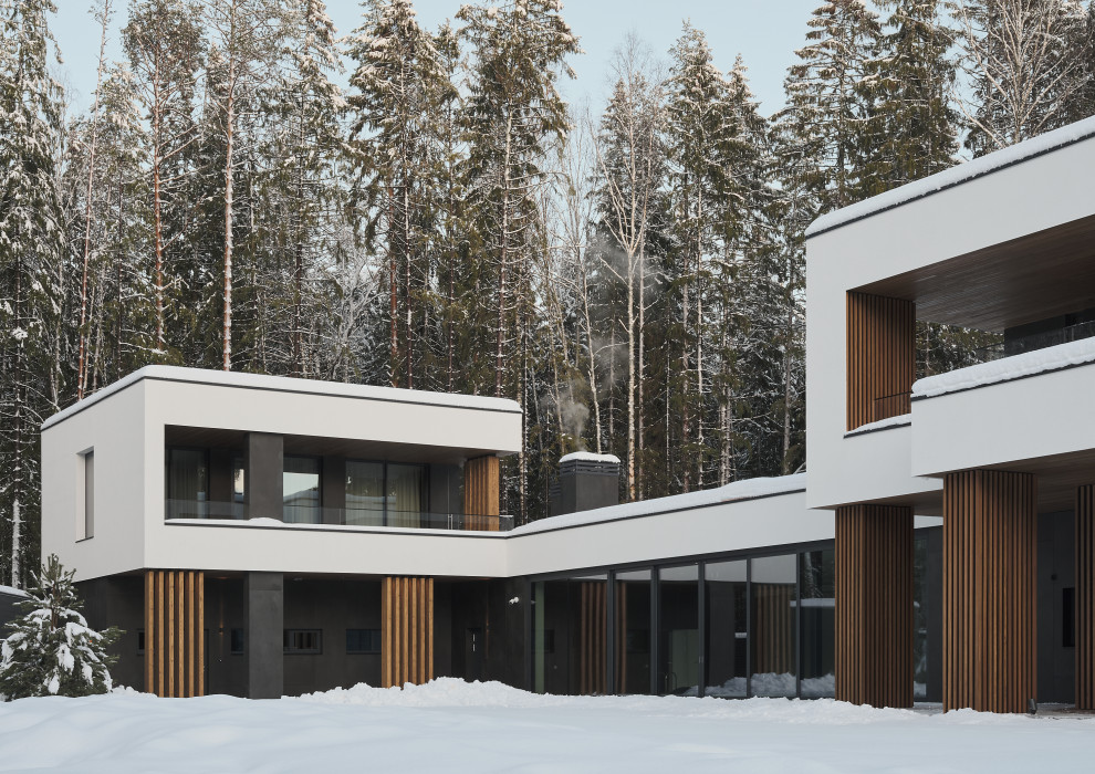 Пример оригинального дизайна: большой, двухэтажный, белый дом в современном стиле с комбинированной облицовкой, плоской крышей, крышей из смешанных материалов, черной крышей и отделкой планкеном