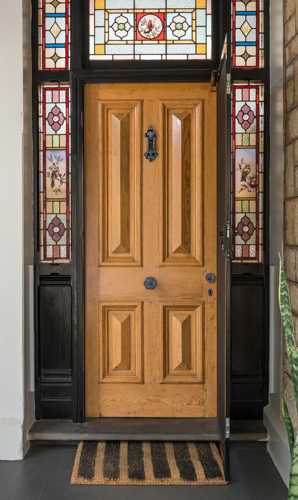 This is an example of a traditional front door in Adelaide with white walls, concrete floors, a single front door, a medium wood front door and black floor.