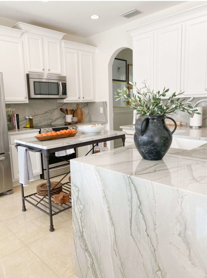 This is an example of a mid-sized modern u-shaped kitchen pantry in Miami with a farmhouse sink, flat-panel cabinets, white cabinets, quartzite benchtops, white splashback, stone slab splashback, stainless steel appliances, ceramic floors, multiple islands, beige floor and white benchtop.