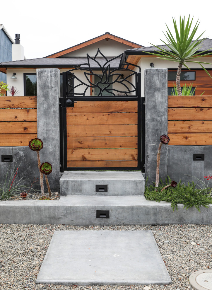 Immagine di un giardino xeriscape minimalista esposto in pieno sole di medie dimensioni e davanti casa in estate con un ingresso o sentiero, pavimentazioni in cemento e recinzione in legno
