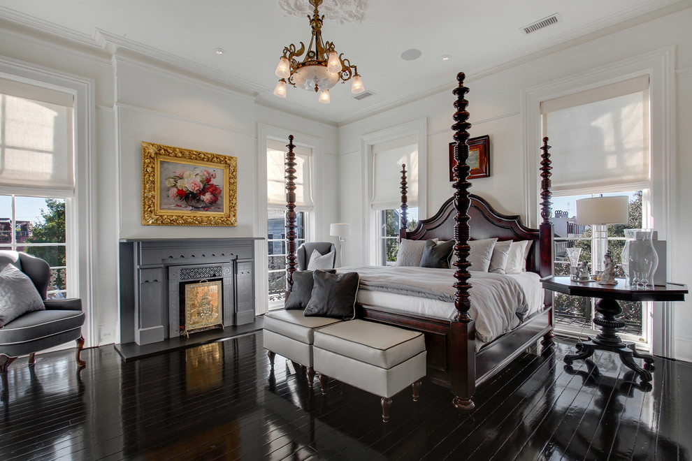 This is an example of a large traditional bedroom in Atlanta with white walls, dark hardwood floors and a standard fireplace.
