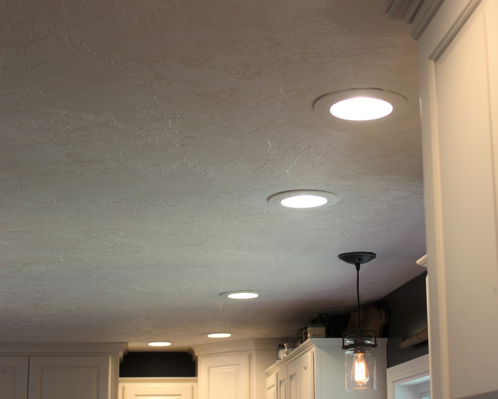 Inspiration for a large rustic l-shaped light wood floor home design remodel in Chicago with a farmhouse sink, raised-panel cabinets, white cabinets, quartz countertops, stainless steel appliances and an island