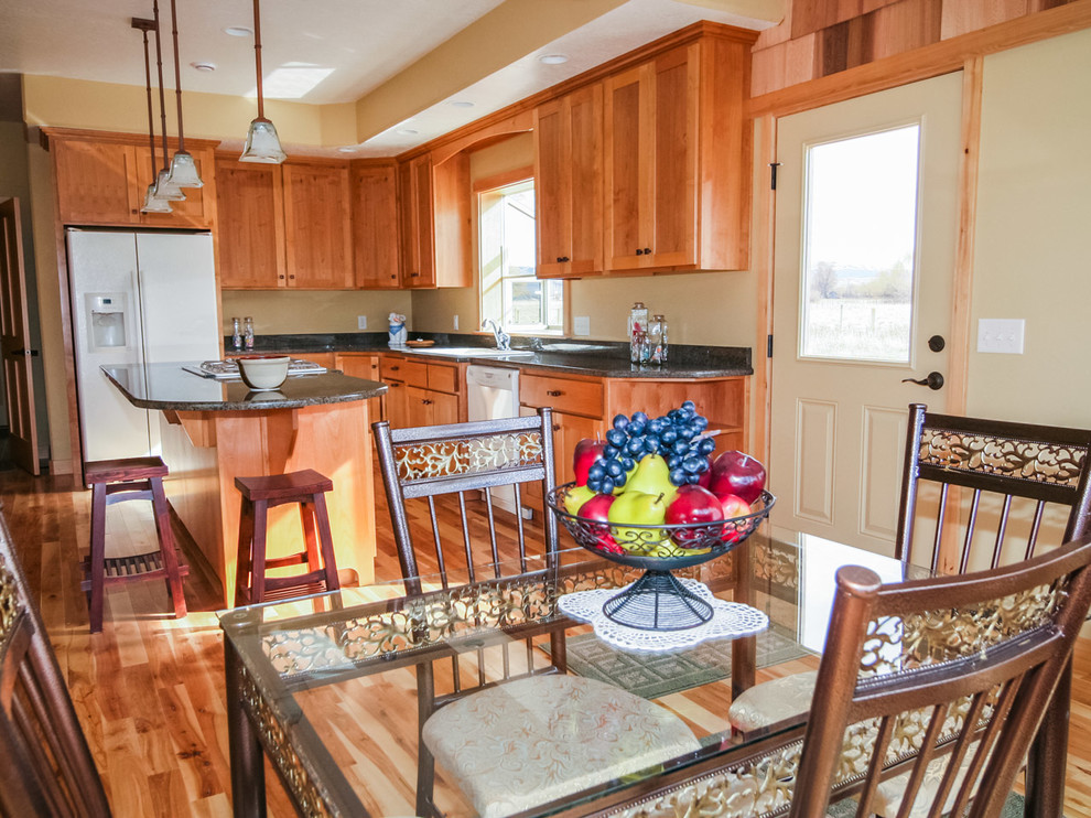 This is an example of a mid-sized arts and crafts u-shaped separate kitchen in Other with a double-bowl sink, recessed-panel cabinets, light wood cabinets, granite benchtops, white appliances, light hardwood floors and with island.