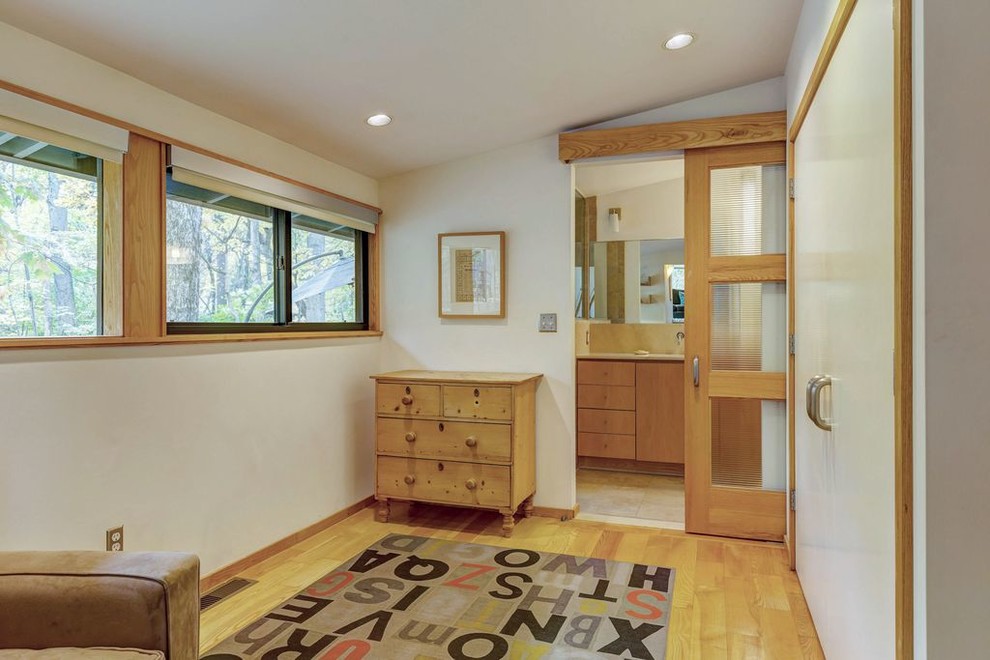 Photo of a small midcentury dressing room in St Louis with flat-panel cabinets, light wood cabinets, light hardwood floors and beige floor.