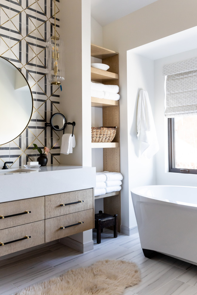 This is an example of a contemporary bathroom in Salt Lake City with flat-panel cabinets, medium wood cabinets, a freestanding bath, black and white tiles, beige walls, a submerged sink, grey floors, white worktops and a floating vanity unit.