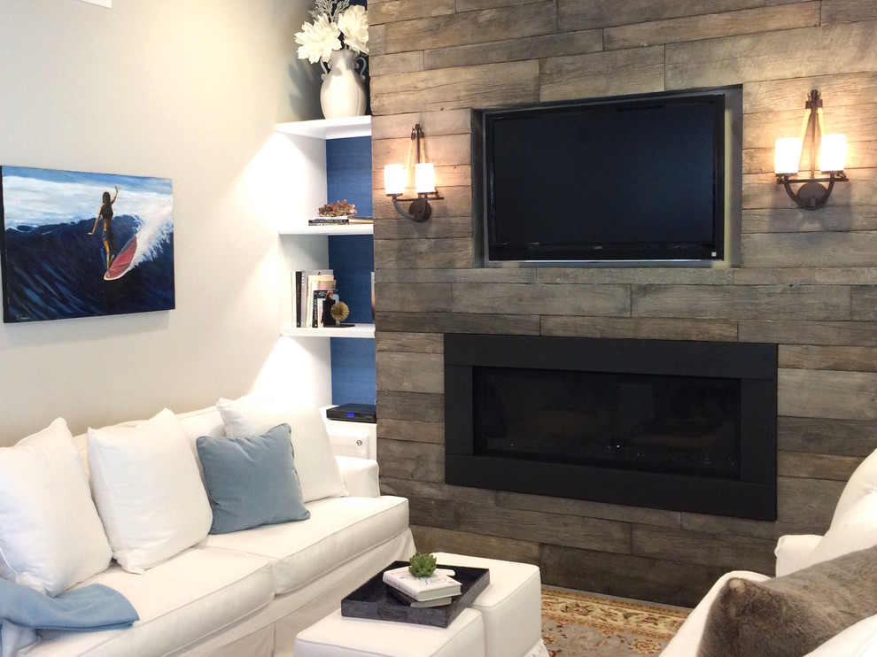This is an example of a small beach style open concept family room in Orange County with white walls, a ribbon fireplace, a wood fireplace surround and a wall-mounted tv.