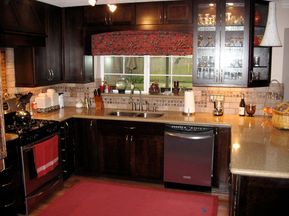 Photo of a mid-sized modern u-shaped kitchen pantry in Houston with an undermount sink, glass-front cabinets, dark wood cabinets, granite benchtops, beige splashback, mosaic tile splashback, stainless steel appliances and laminate floors.
