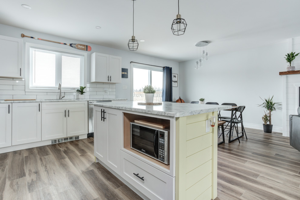 Example of a minimalist vinyl floor and brown floor eat-in kitchen design with shaker cabinets, white cabinets, ceramic backsplash and stainless steel appliances