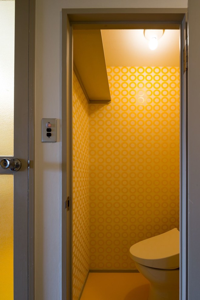 Photo of a small modern powder room in Other with open cabinets, a two-piece toilet, yellow walls, vinyl floors, a wall-mount sink, yellow floor, a floating vanity, wallpaper and wallpaper.