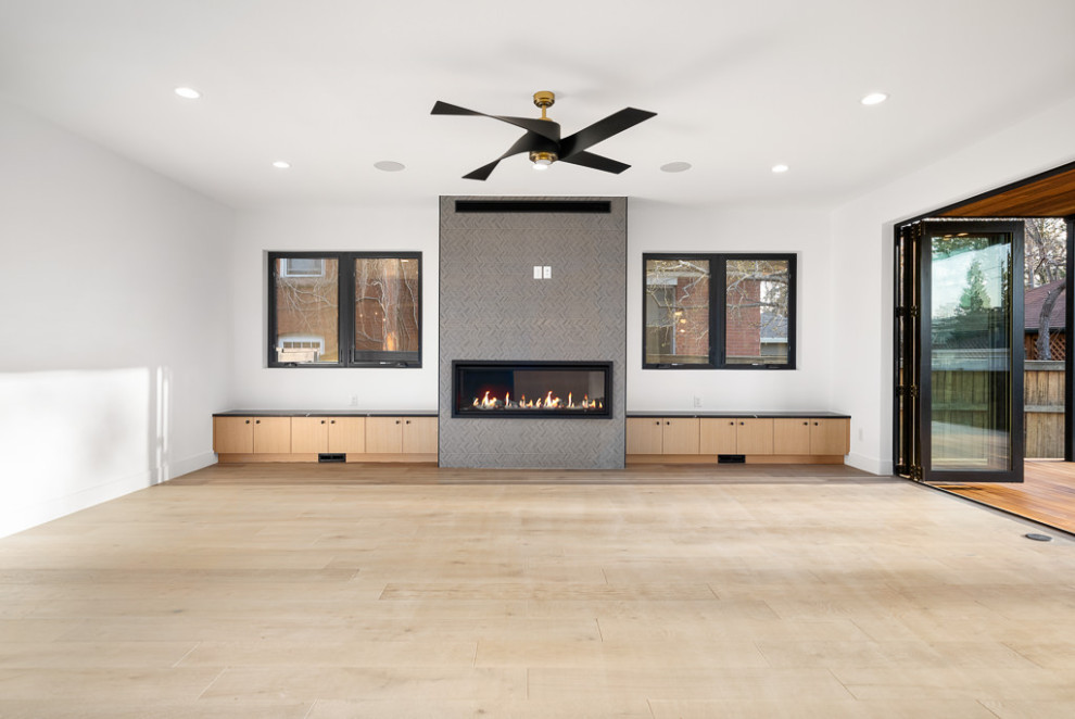 Design ideas for a large industrial open concept living room in Denver with white walls, light hardwood floors, a standard fireplace, a tile fireplace surround, brown floor and exposed beam.