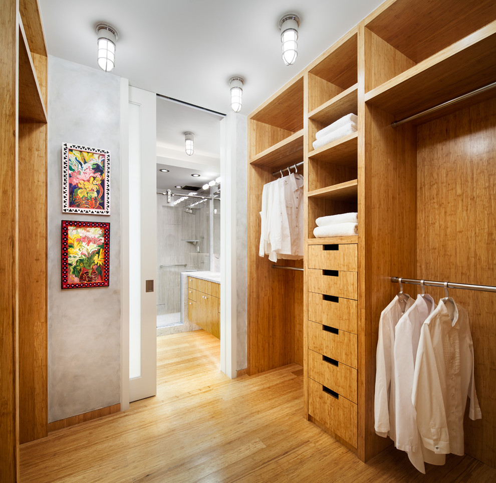 Small contemporary gender-neutral walk-in wardrobe in New York with open cabinets, light wood cabinets and bamboo floors.