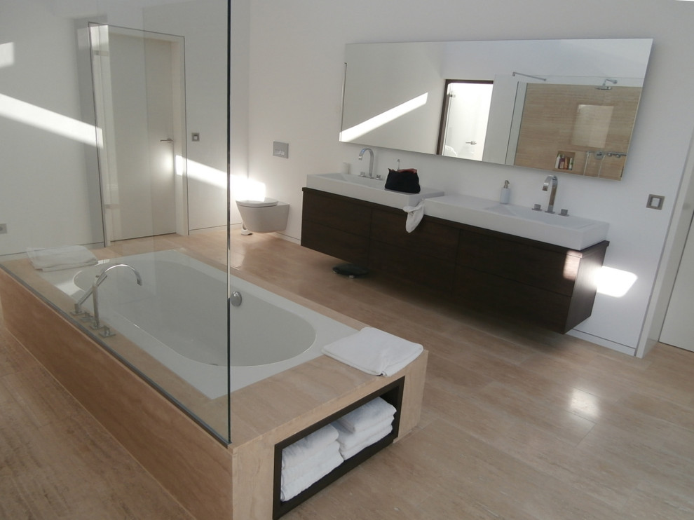Example of a huge minimalist master wood-look tile floor, beige floor and double-sink bathroom design with an undermount tub, a wall-mount toilet, white walls, a built-in vanity, flat-panel cabinets, dark wood cabinets, a vessel sink and wood countertops