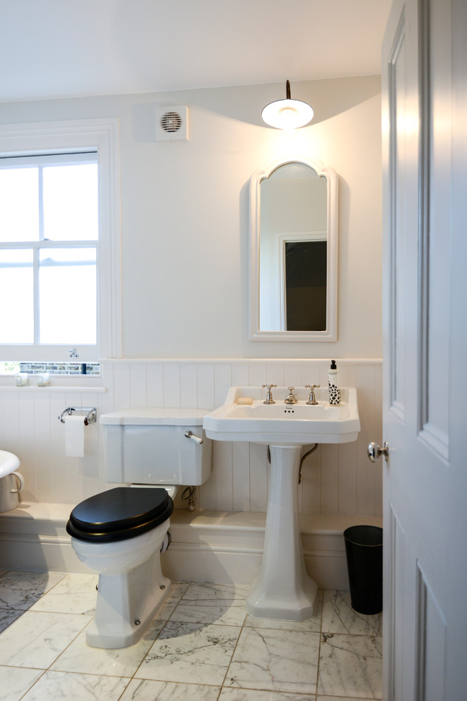 This is an example of a traditional bathroom in London with a pedestal sink, a two-piece toilet and white tile.