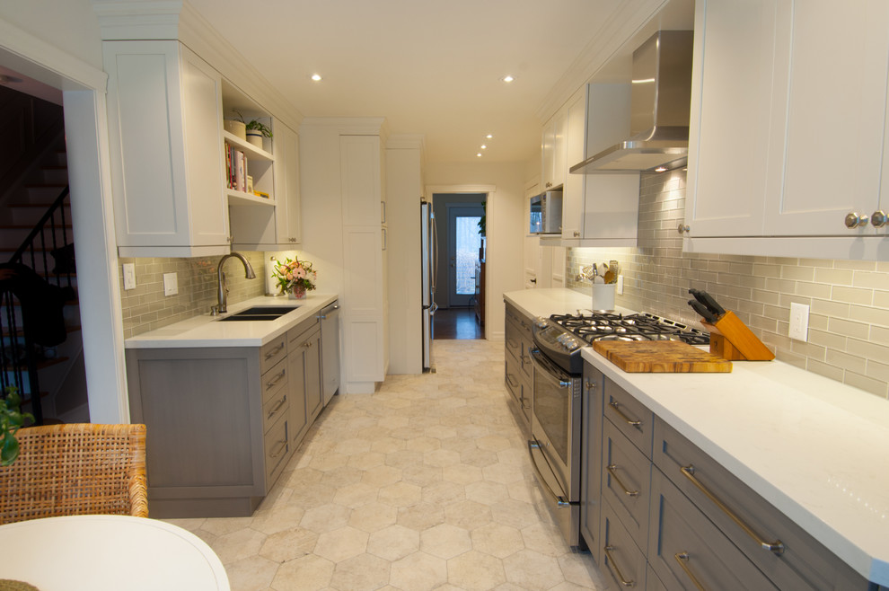 Inspiration for a mid-sized transitional galley ceramic tile enclosed kitchen remodel in Toronto with a double-bowl sink, shaker cabinets, white cabinets, quartzite countertops, gray backsplash, glass tile backsplash, stainless steel appliances and no island