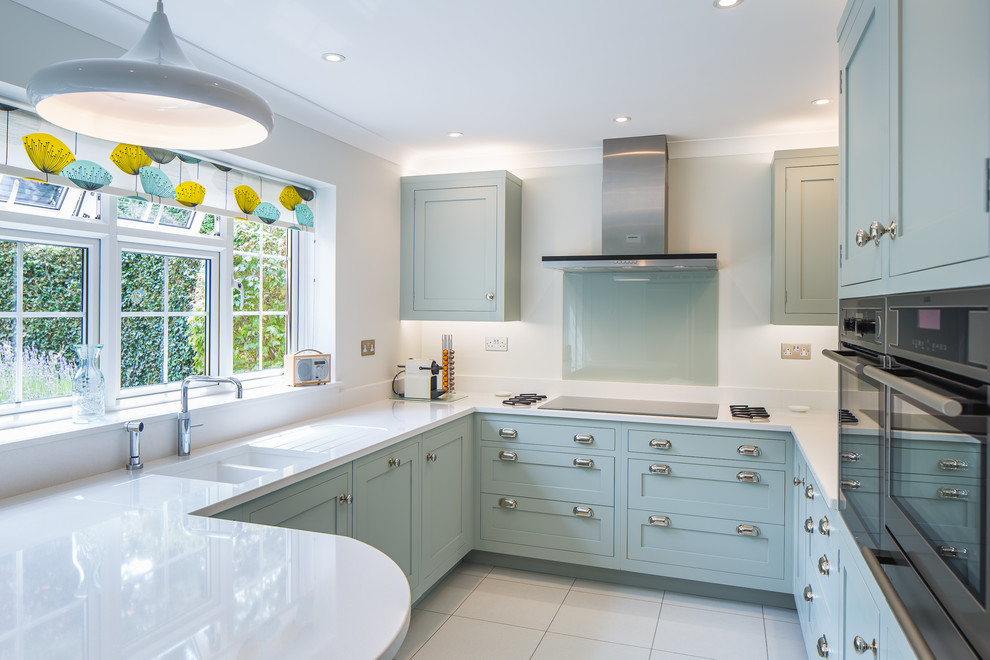 Design ideas for a mid-sized contemporary u-shaped eat-in kitchen in Oxfordshire with a drop-in sink, shaker cabinets, turquoise cabinets, laminate benchtops, white splashback, glass sheet splashback, stainless steel appliances, slate floors, a peninsula and white floor.