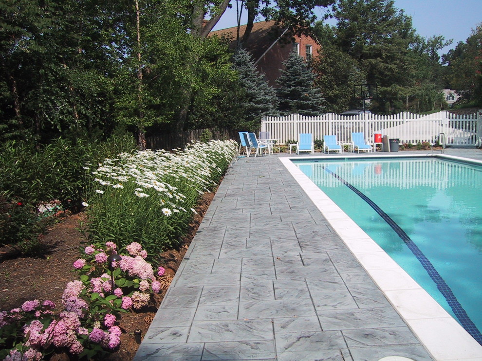 Example of a mid-sized transitional backyard stamped concrete and rectangular lap pool house design in Baltimore