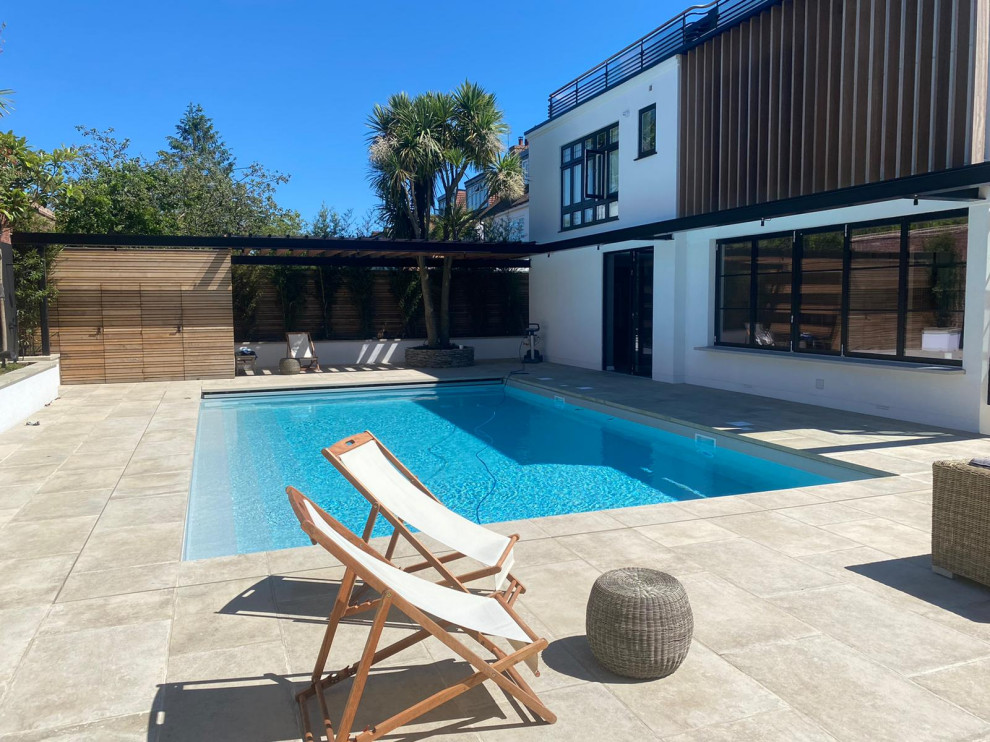 Modelo de piscina moderna de tamaño medio rectangular en patio trasero con paisajismo de piscina y adoquines de piedra natural