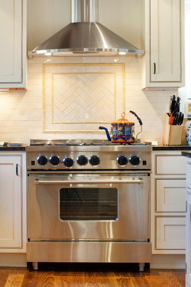 Kitchen - transitional u-shaped medium tone wood floor kitchen idea in New York with a farmhouse sink, beaded inset cabinets, white cabinets, granite countertops, beige backsplash, subway tile backsplash, stainless steel appliances and an island