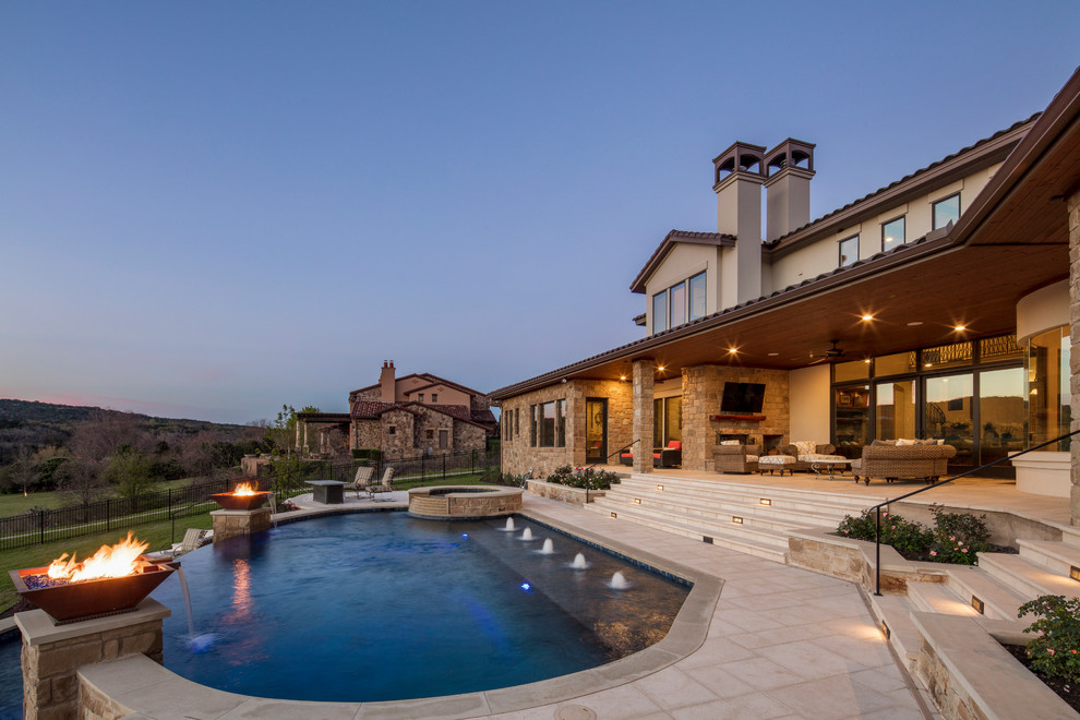 This is an example of a large mediterranean backyard kidney-shaped infinity pool in Austin with a hot tub and concrete pavers.