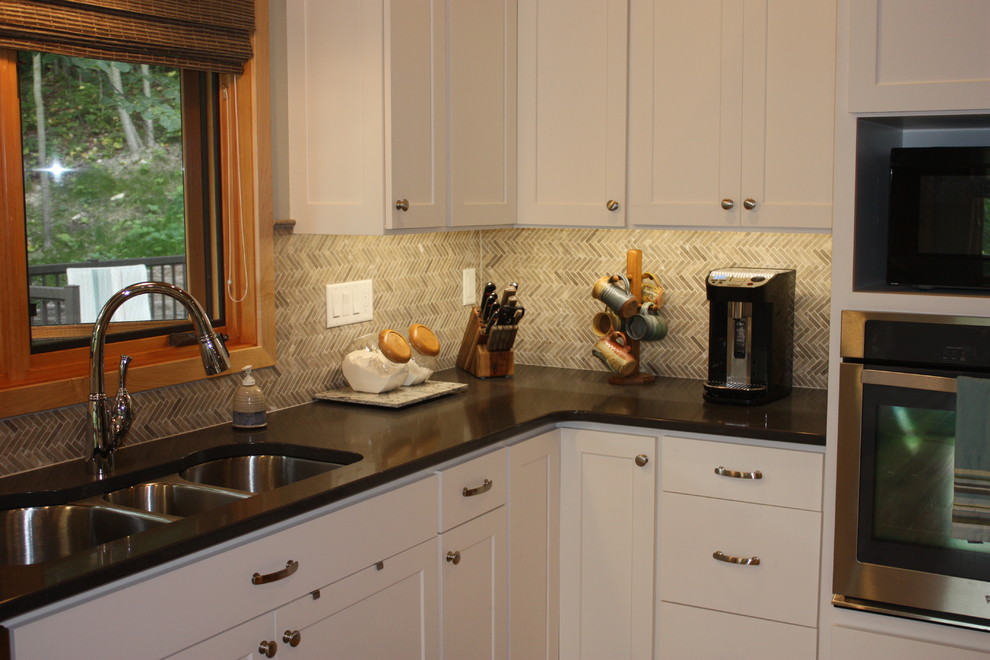 Large transitional l-shaped open concept kitchen photo with a triple-bowl sink, recessed-panel cabinets, white cabinets, solid surface countertops, multicolored backsplash, mosaic tile backsplash, stainless steel appliances and an island