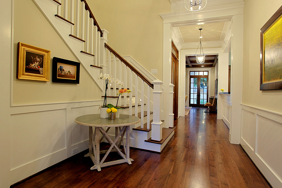 Photo of a mid-sized traditional foyer in Houston with yellow walls, dark hardwood floors, a double front door and a glass front door.