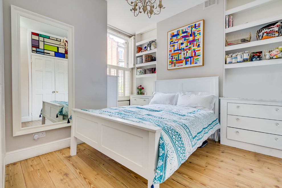 Transitional bedroom in London with grey walls, light hardwood floors and beige floor.