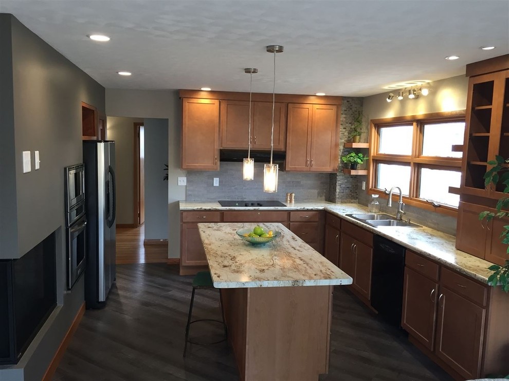 Photo of a mid-sized midcentury l-shaped kitchen in Cedar Rapids with a double-bowl sink, shaker cabinets, brown cabinets, grey splashback, stainless steel appliances, with island, brown floor, laminate benchtops, stone tile splashback and vinyl floors.