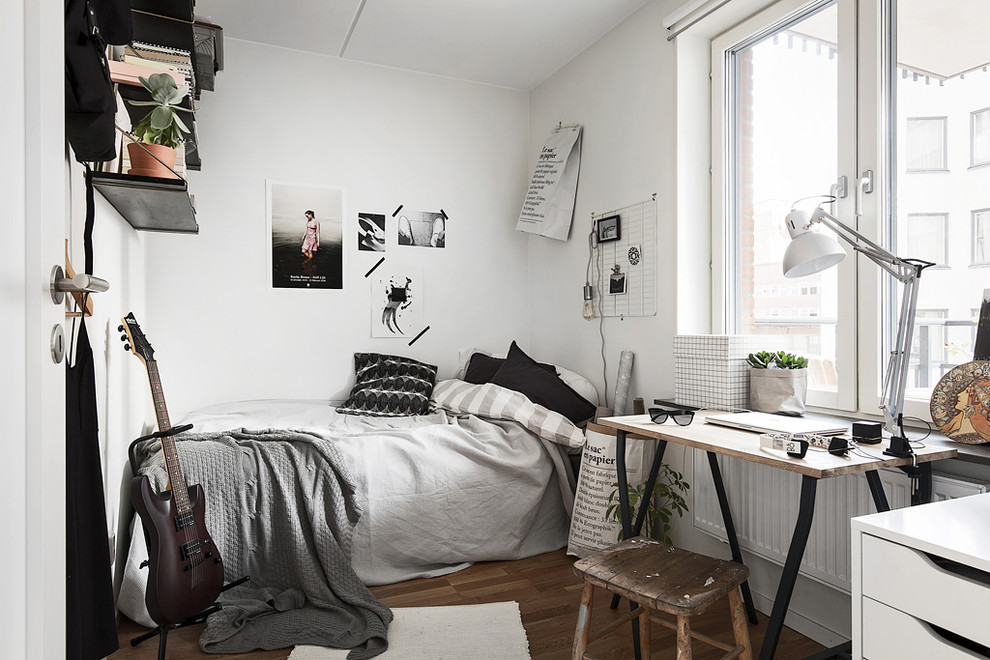 This is an example of a mid-sized scandinavian gender-neutral kids' room in Stockholm with white walls and dark hardwood floors.