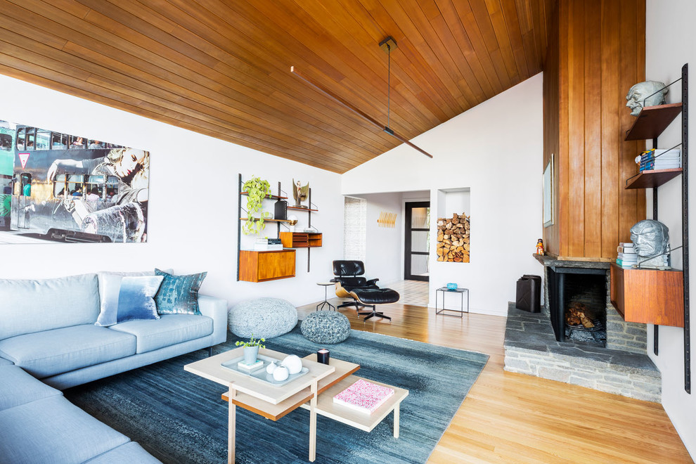 Large midcentury open concept living room in Portland with white walls, light hardwood floors, a standard fireplace, a stone fireplace surround, no tv and beige floor.