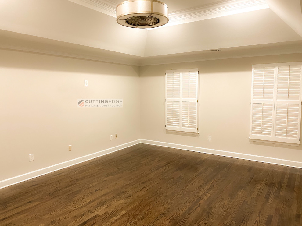 Imagen de dormitorio principal y blanco clásico renovado grande sin chimenea con paredes grises, suelo de madera en tonos medios, suelo marrón y bandeja