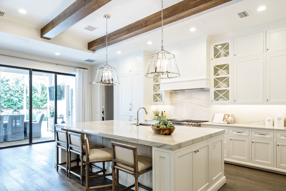 This is an example of a large transitional l-shaped open plan kitchen in Orlando with an undermount sink, recessed-panel cabinets, white cabinets, marble benchtops, white splashback, marble splashback, panelled appliances, dark hardwood floors, with island and brown floor.