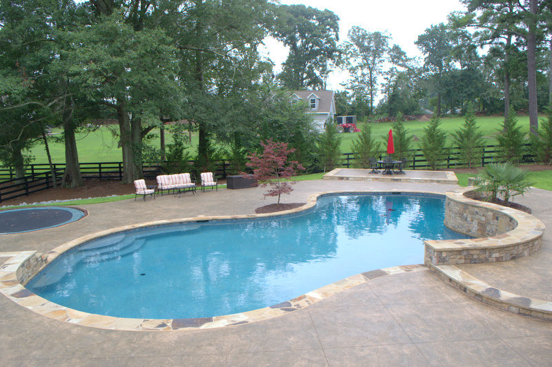 This is an example of a large traditional backyard custom-shaped pool in Atlanta with a pool house and stamped concrete.