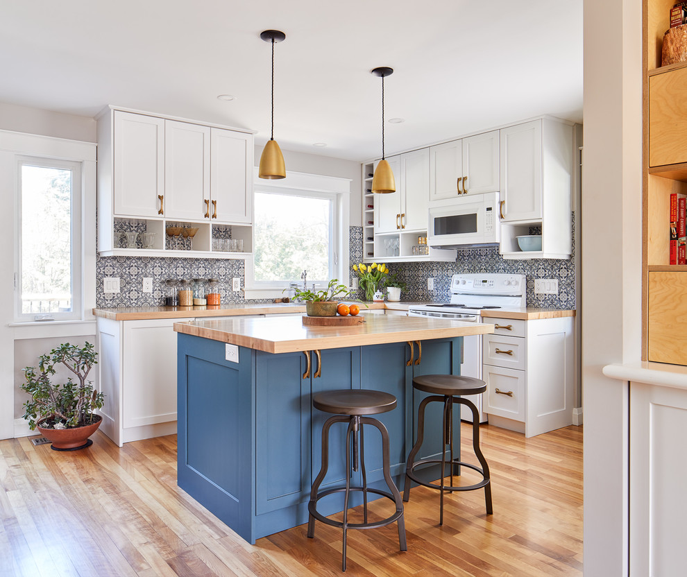 Small transitional l-shaped eat-in kitchen in Ottawa with a drop-in sink, shaker cabinets, blue cabinets, wood benchtops, blue splashback, ceramic splashback, white appliances, medium hardwood floors and with island.