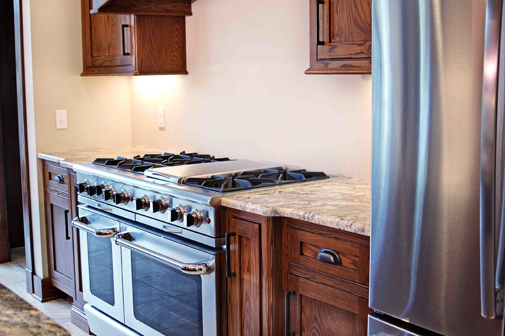 Example of a mountain style kitchen design with dark wood cabinets, granite countertops and an island