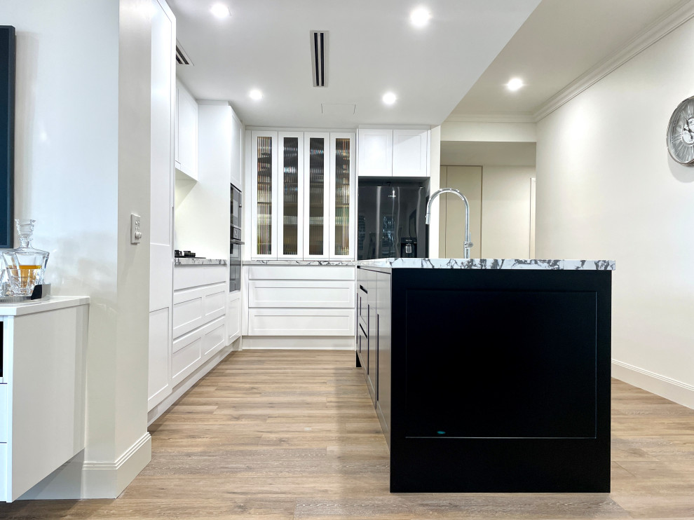This is an example of a mid-sized l-shaped eat-in kitchen in Sydney with an undermount sink, shaker cabinets, black cabinets, quartz benchtops, multi-coloured splashback, engineered quartz splashback, black appliances, light hardwood floors, with island, brown floor and multi-coloured benchtop.