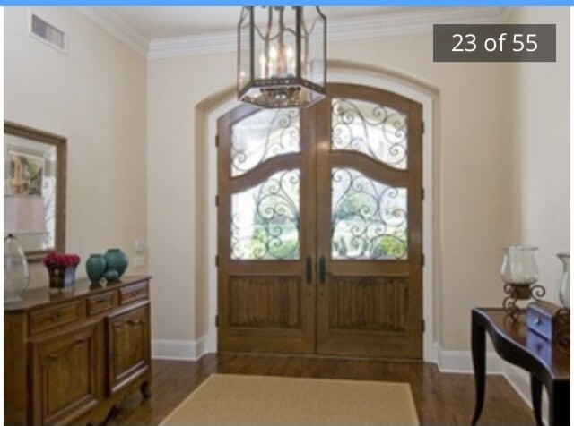 This is an example of a large transitional foyer in Los Angeles with white walls, dark hardwood floors, a double front door and a dark wood front door.