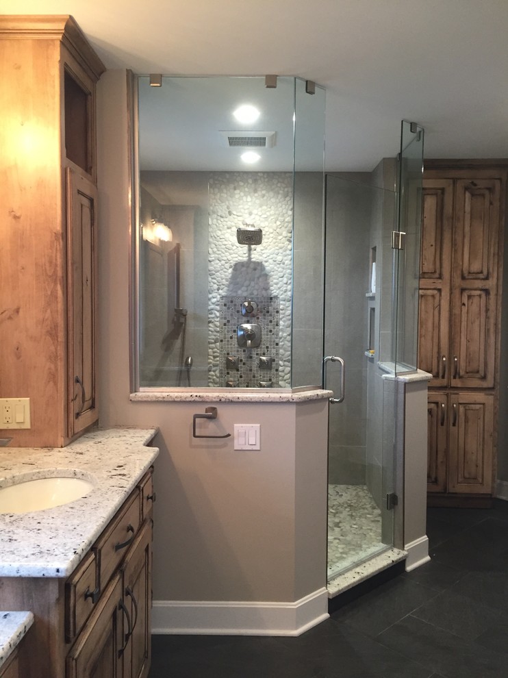 Photo of a mid-sized traditional master bathroom in Other with raised-panel cabinets, medium wood cabinets, a drop-in tub, an alcove shower, gray tile, mosaic tile, beige walls, slate floors, an undermount sink and granite benchtops.
