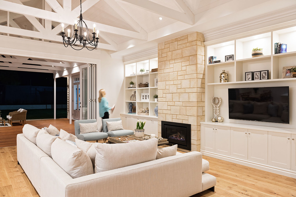 Photo of a large transitional open concept living room in Hobart with white walls, medium hardwood floors, a standard fireplace, a stone fireplace surround, a wall-mounted tv and beige floor.