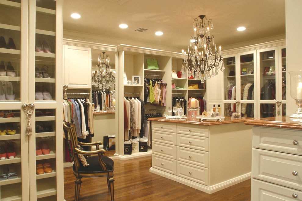 Expansive traditional gender-neutral walk-in wardrobe in Birmingham with raised-panel cabinets, white cabinets, medium hardwood floors and brown floor.