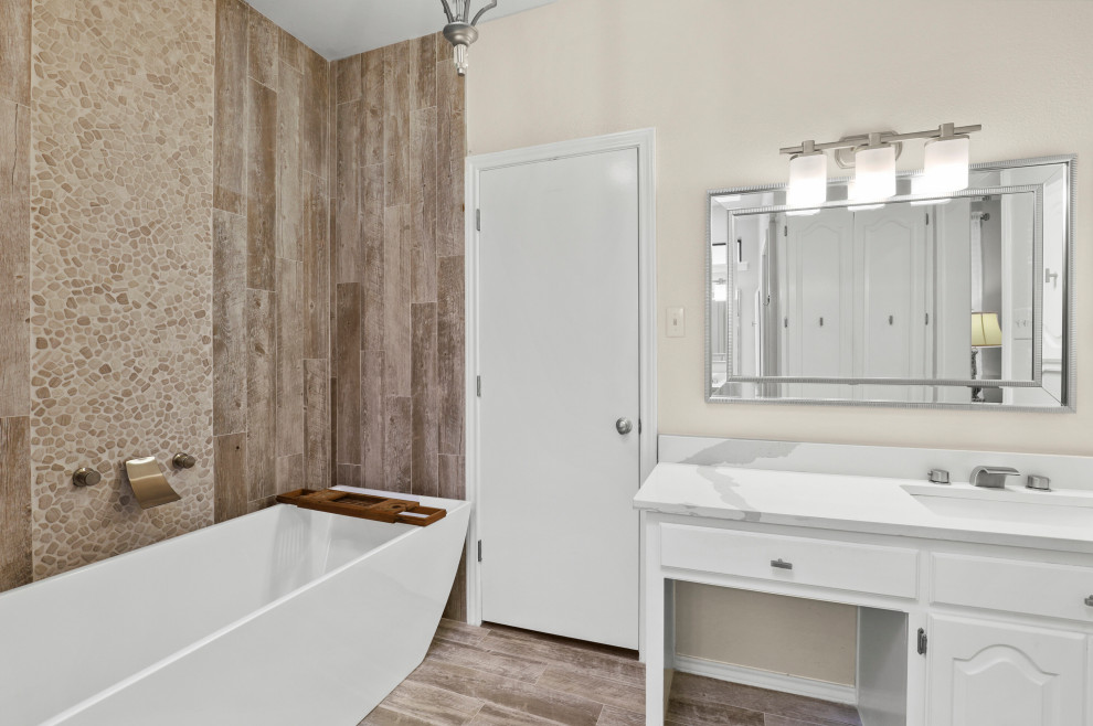 This is an example of a mid-sized modern master bathroom in Dallas with raised-panel cabinets, white cabinets, a drop-in tub, a shower/bathtub combo, a one-piece toilet, gray tile, wood-look tile, beige walls, ceramic floors, a console sink, quartzite benchtops, beige floor, a shower curtain, white benchtops, a single vanity and a built-in vanity.