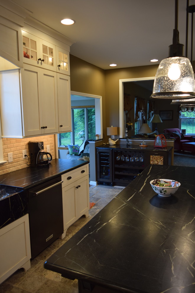 Inspiration for a transitional l-shaped ceramic tile kitchen remodel with an undermount sink, shaker cabinets, white cabinets, quartz countertops, beige backsplash, subway tile backsplash, black appliances and an island