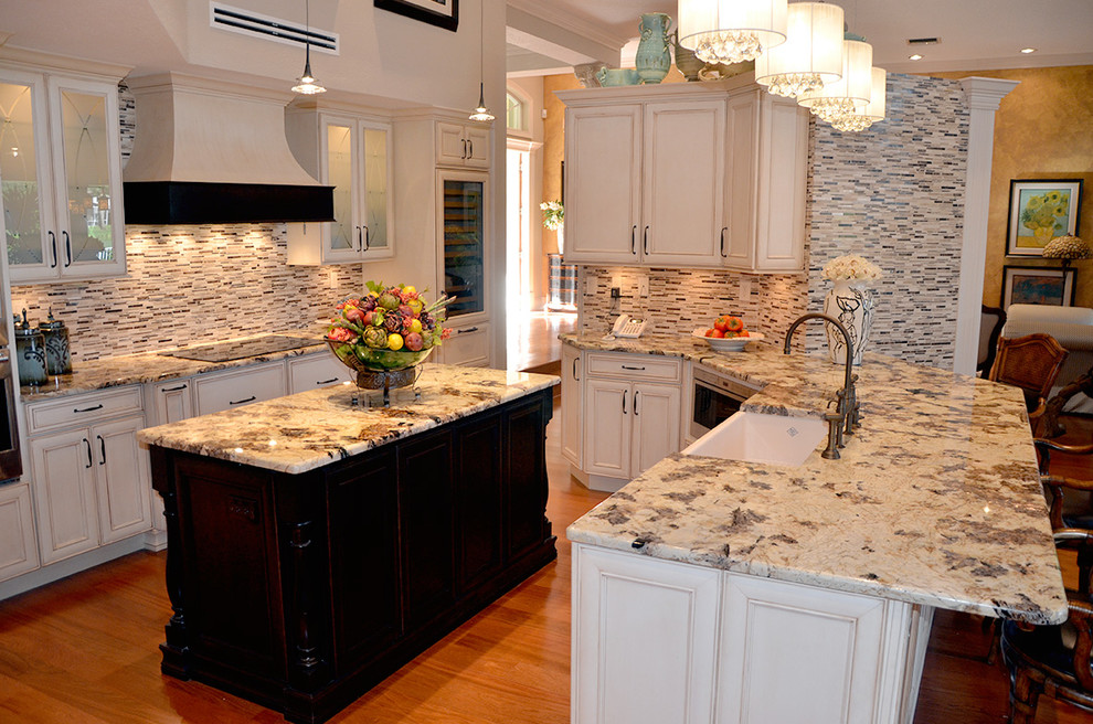 Large transitional medium tone wood floor open concept kitchen photo in Miami with a farmhouse sink, recessed-panel cabinets, white cabinets, granite countertops, multicolored backsplash, paneled appliances and an island