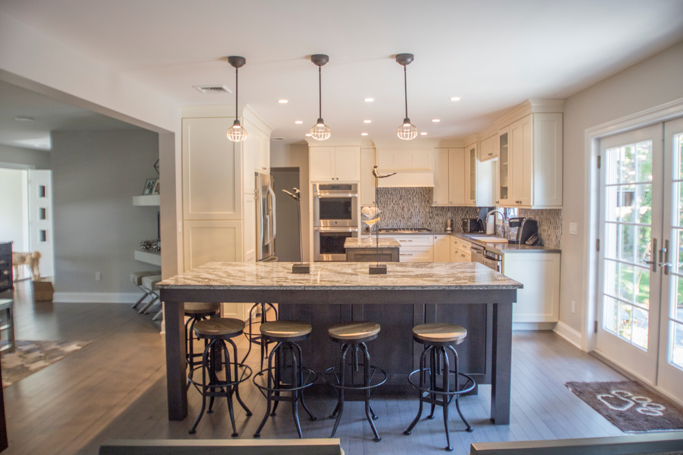Inspiration for a mid-sized transitional l-shaped dark wood floor eat-in kitchen remodel in New York with an undermount sink, recessed-panel cabinets, beige cabinets, quartz countertops, multicolored backsplash, subway tile backsplash, stainless steel appliances and two islands