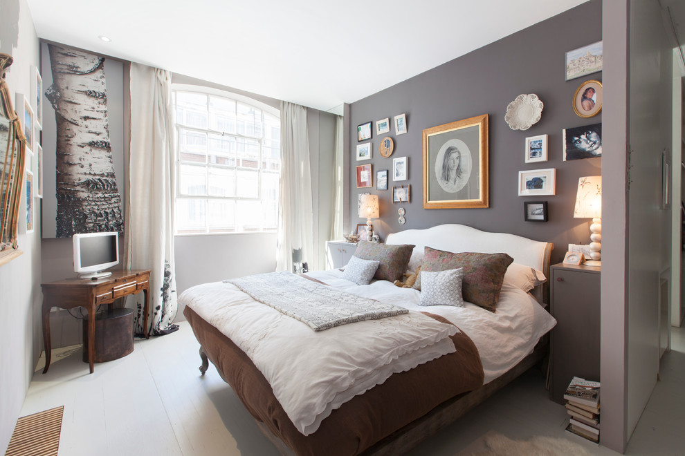 Mid-sized eclectic guest bedroom in London with grey walls, painted wood floors and white floor.