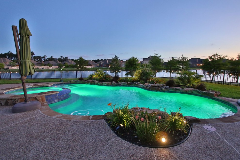 Photo of a mid-sized contemporary backyard custom-shaped natural pool in Houston with a hot tub and concrete slab.