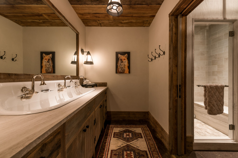 Country bathroom in Other with flat-panel cabinets, dark wood cabinets, an alcove shower, gray tile, beige walls, a trough sink, black floor, a hinged shower door and grey benchtops.