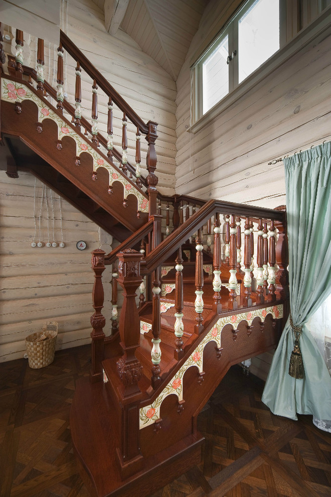 Photo of a large country wood u-shaped staircase in Other with wood risers.
