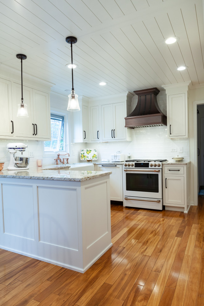 Mid-sized country l-shaped eat-in kitchen in Chicago with a farmhouse sink, beaded inset cabinets, white cabinets, granite benchtops, white splashback, porcelain splashback, white appliances, light hardwood floors, a peninsula, orange floor, beige benchtop and timber.